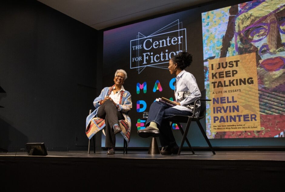 Two women seated in chairs on a stage laugh in the midst of a book discussion. Behind them, a projector screen displays the logos for the Center for Fiction and MacDowell and an image of the cover of Nell Painter's book, I Just Keep Talking.