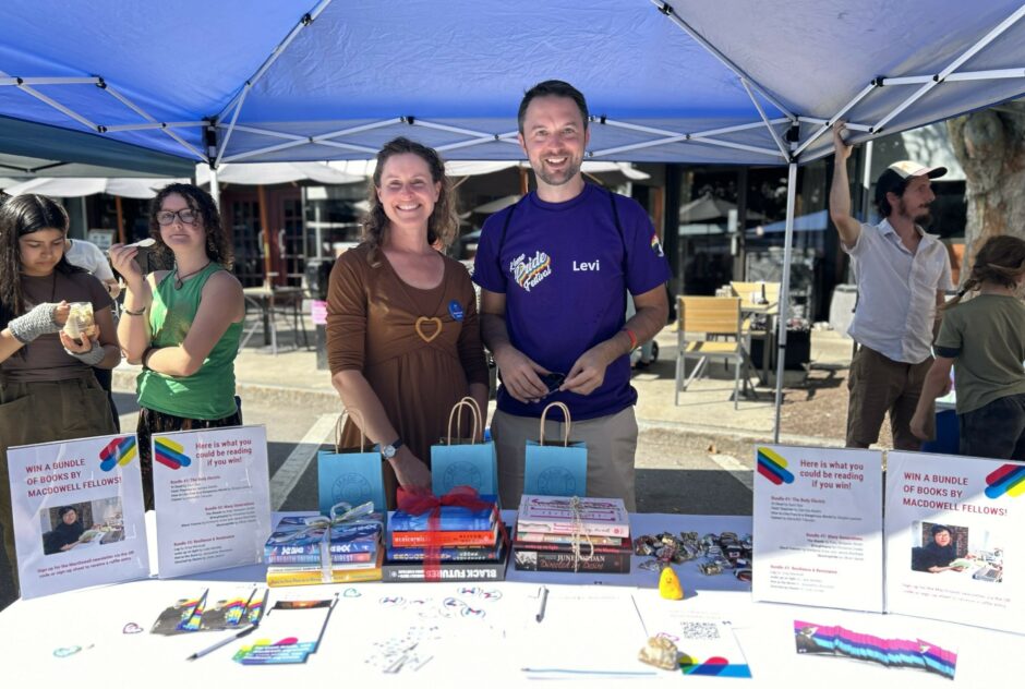 Two people pose for a picture while running a booth at a street festival