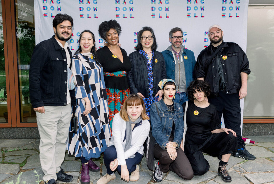 A group of people standing and crouching pose for a photo in front of a step and repeat