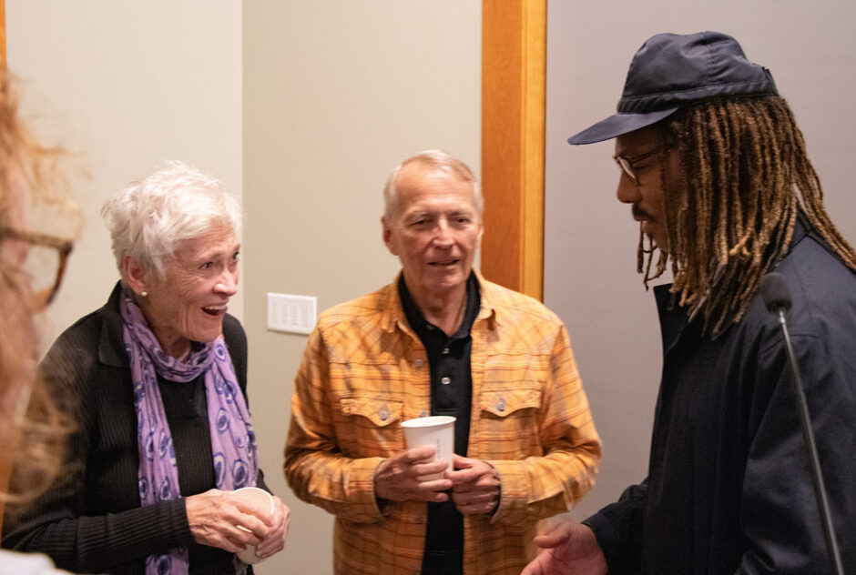 Three people stand in a circle and talk with one another