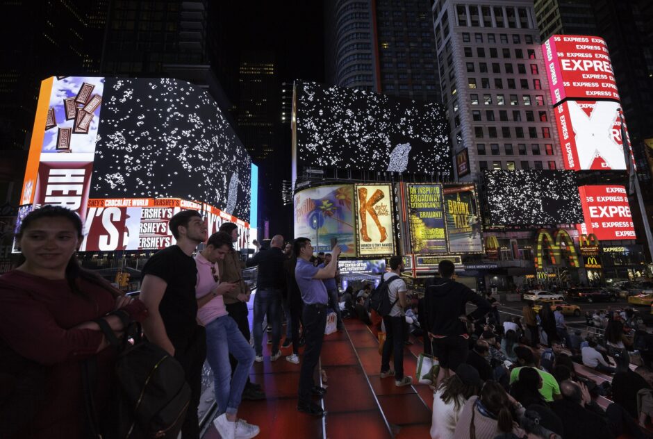 On multiple billboard screens above a city street at night, stills from "Pattern Language" by Peter Burr are projected for onlookers and passerby.