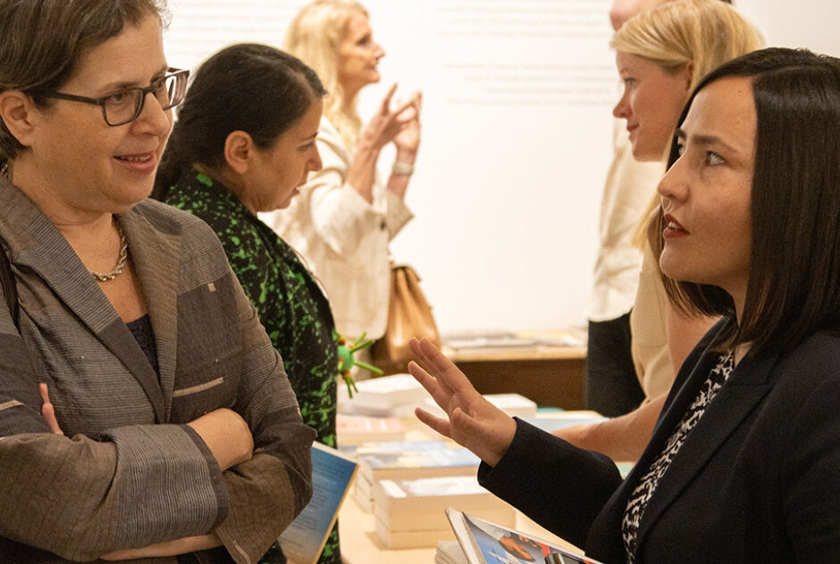 Zahra Nader (right) speaking with a person in a crowded room.