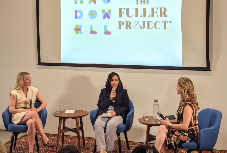 Three women sit in chairs on a stage holding microphones, in discussion. Above and behind them, a projector screen displays the logos for MacDowell and The Fuller Project.