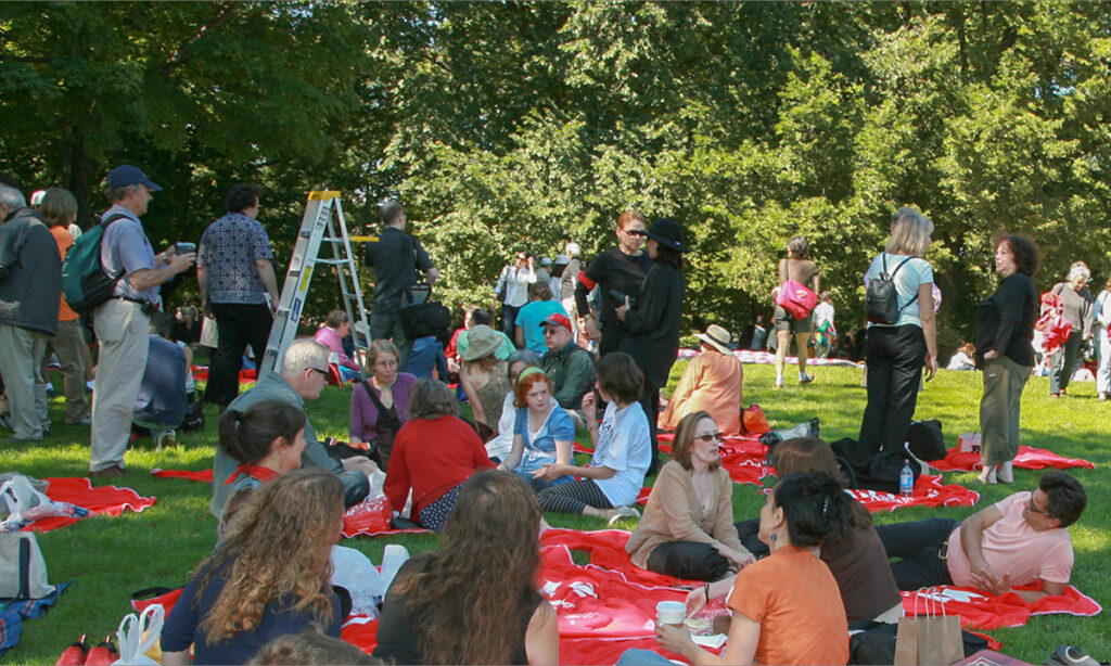 Many people lounge and picnic on blankets on a grassy lawn.