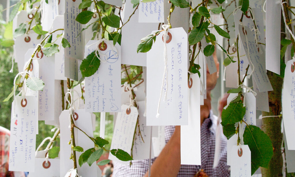 Paper tags with handwritten messages hang from tree branches.