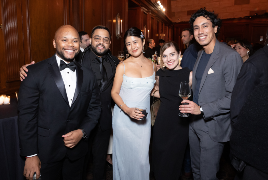 A group of people in formal wear pose together and smile at the camera