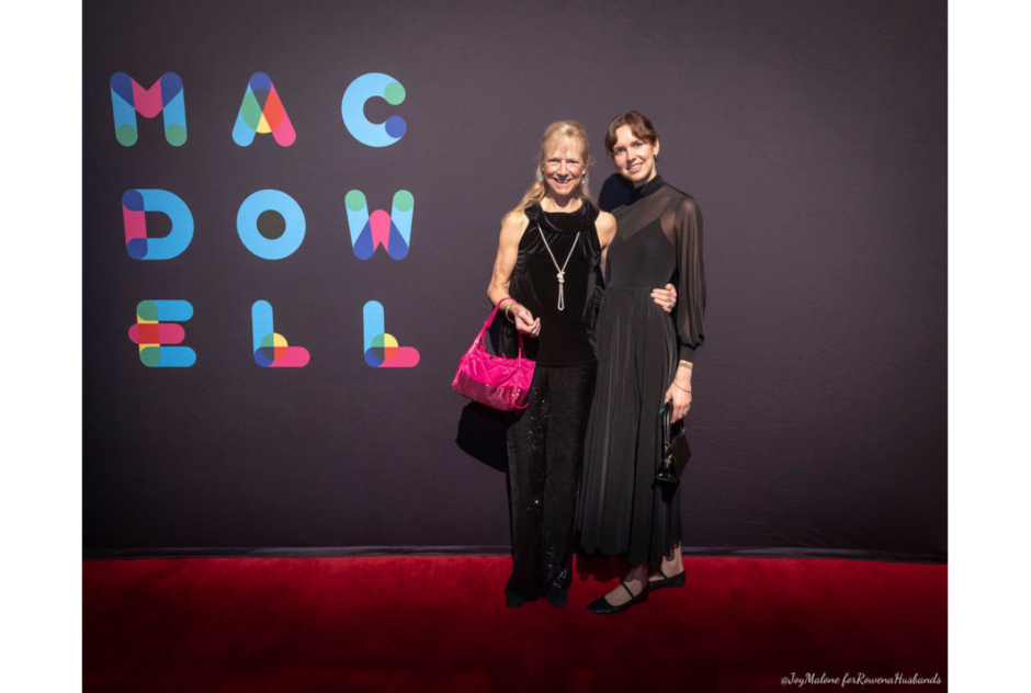 A middle aged white woman and a young white woman, both in black dresses, pose for a photo