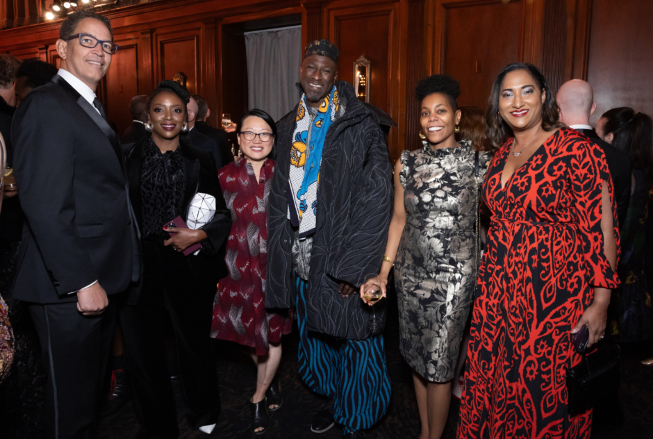 A diverse group of people in colorful formal wear smile for a photo at a party