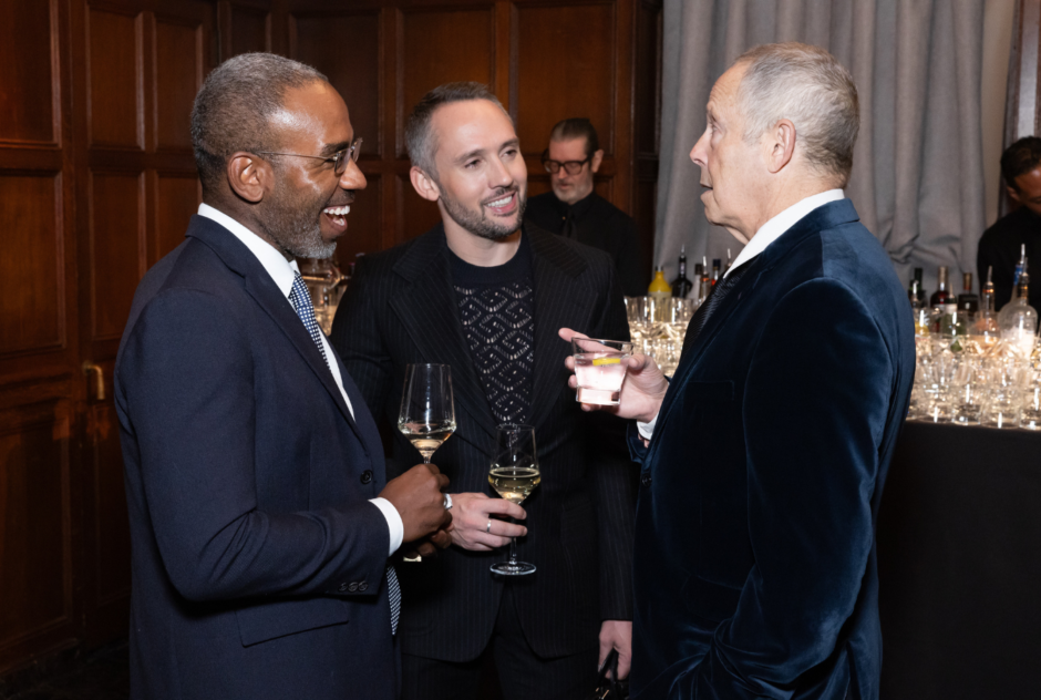 A group of three men are in conversation while holding drinks