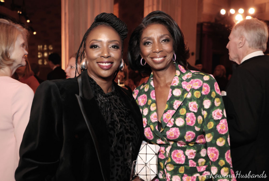 Two women in formal wear smile and pose for a photo