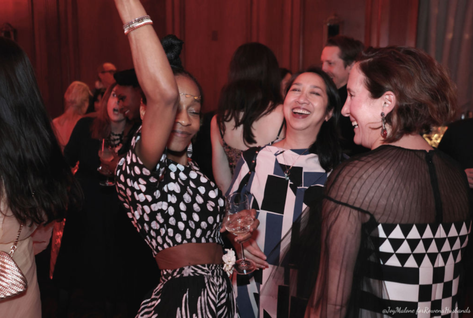 A group of women laugh and dance at a party