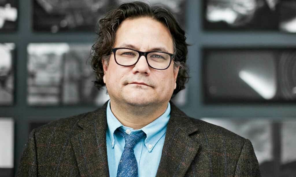 Jesse Wente looking at the camera wearing a brown jacket, blue shirt and tie.