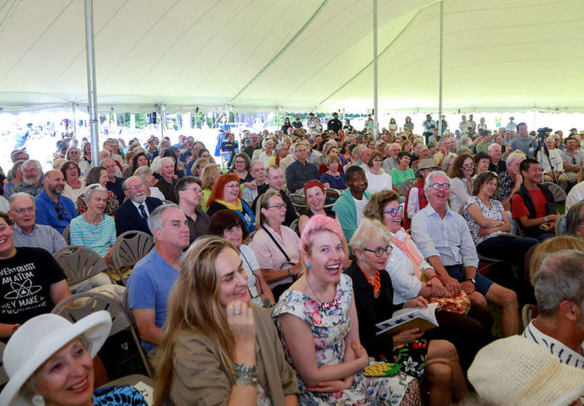 A large crowd smiles and laughs as speakers present during the Medal Day Ceremony