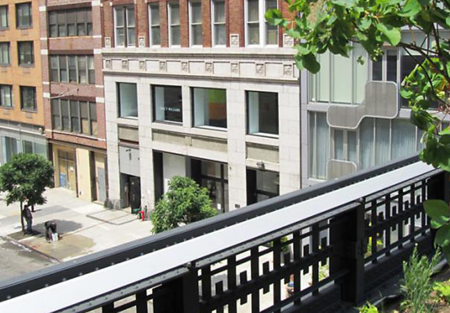 View from a balcony looking down on a quite city street. The balcony is decorated with plants.