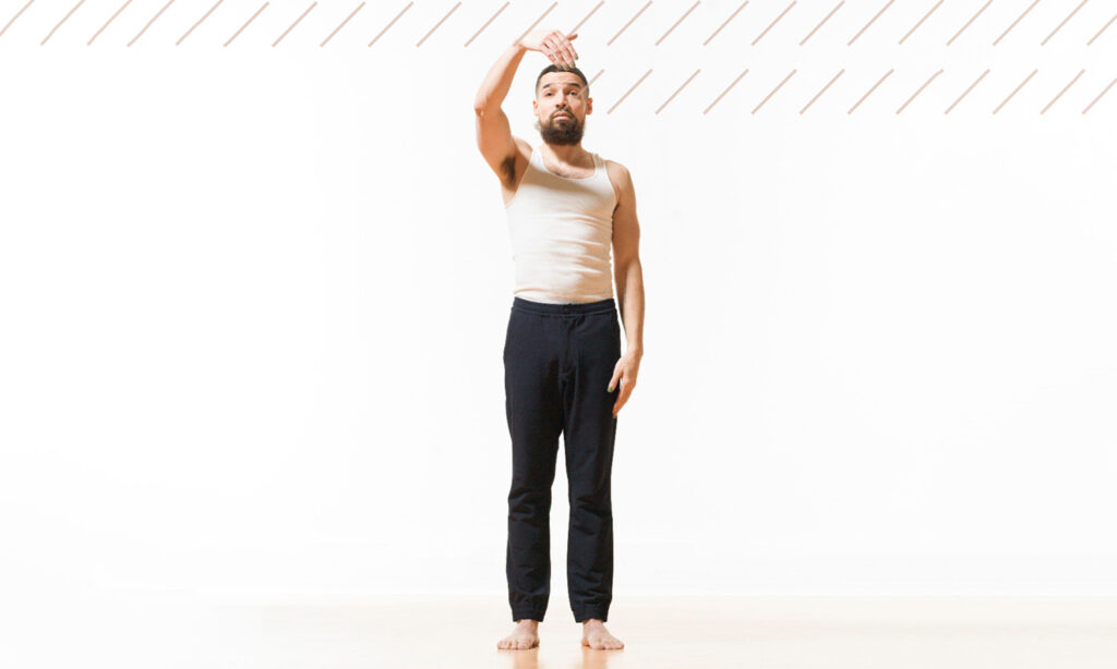 Man standing, gesturing with his hand in a white room